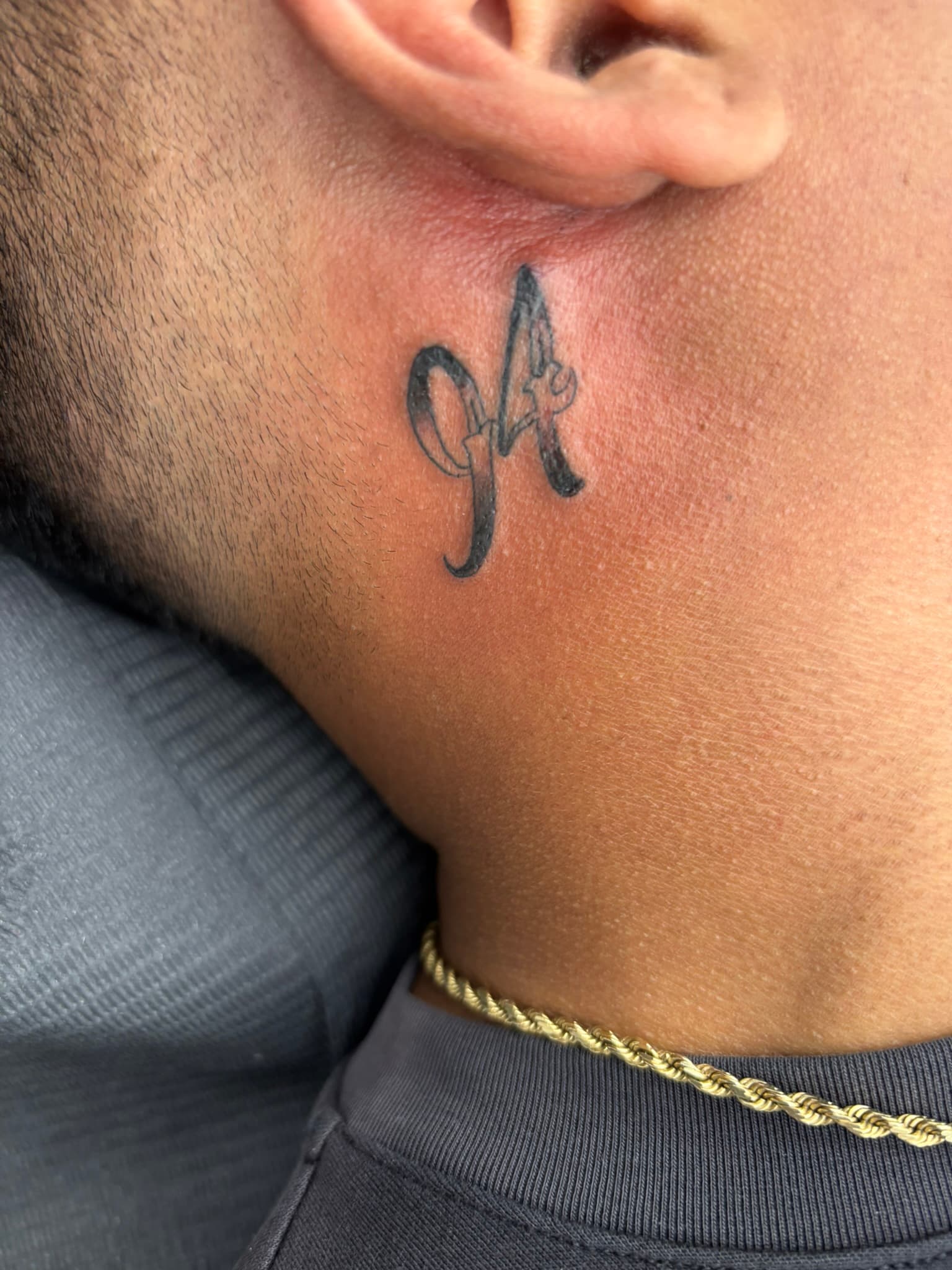 Fine line numeral tattoo behind the ear by Isaac Mackenzie