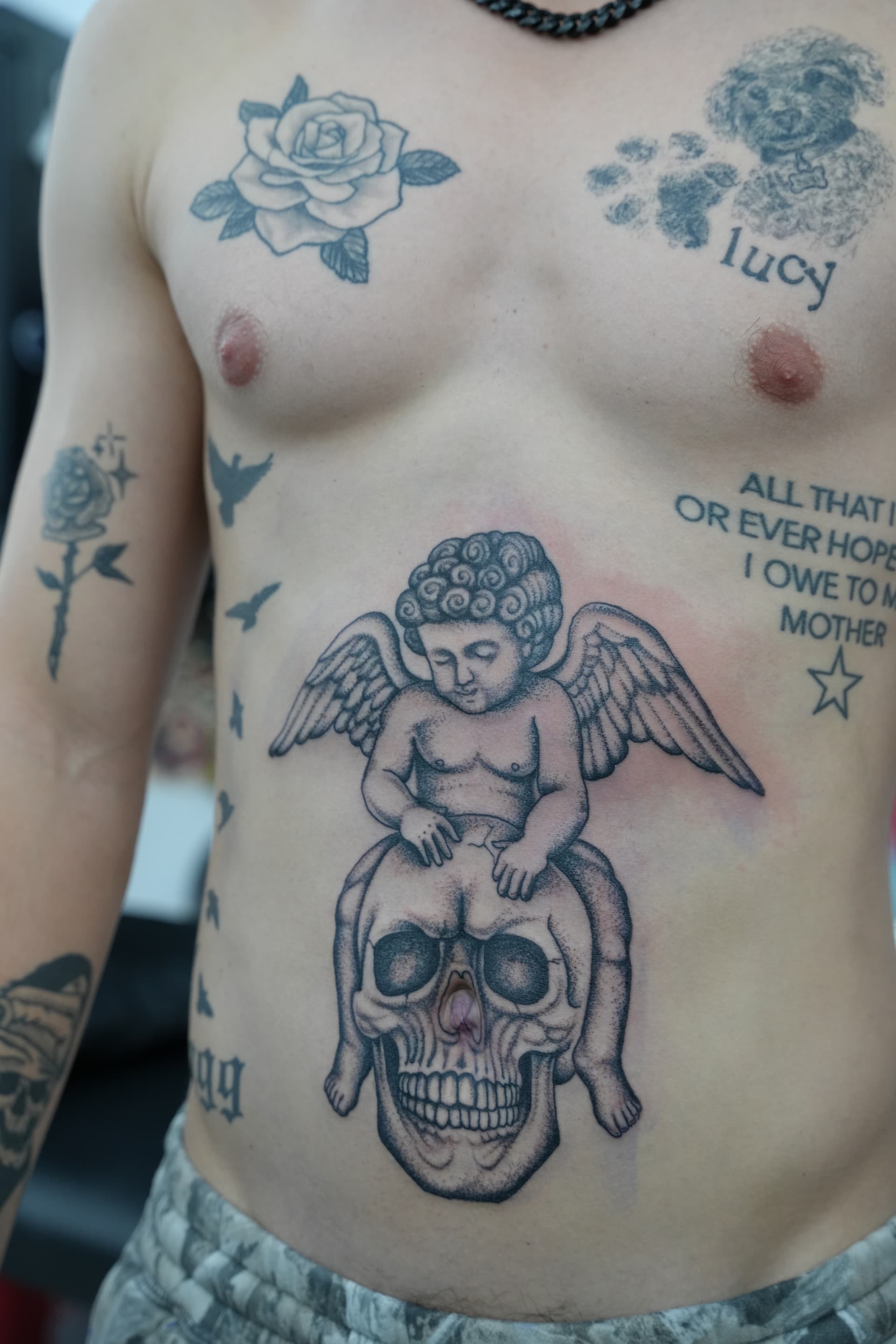 Fine line cherub and skull stomach piece tattoo by Isaac Mackenzie