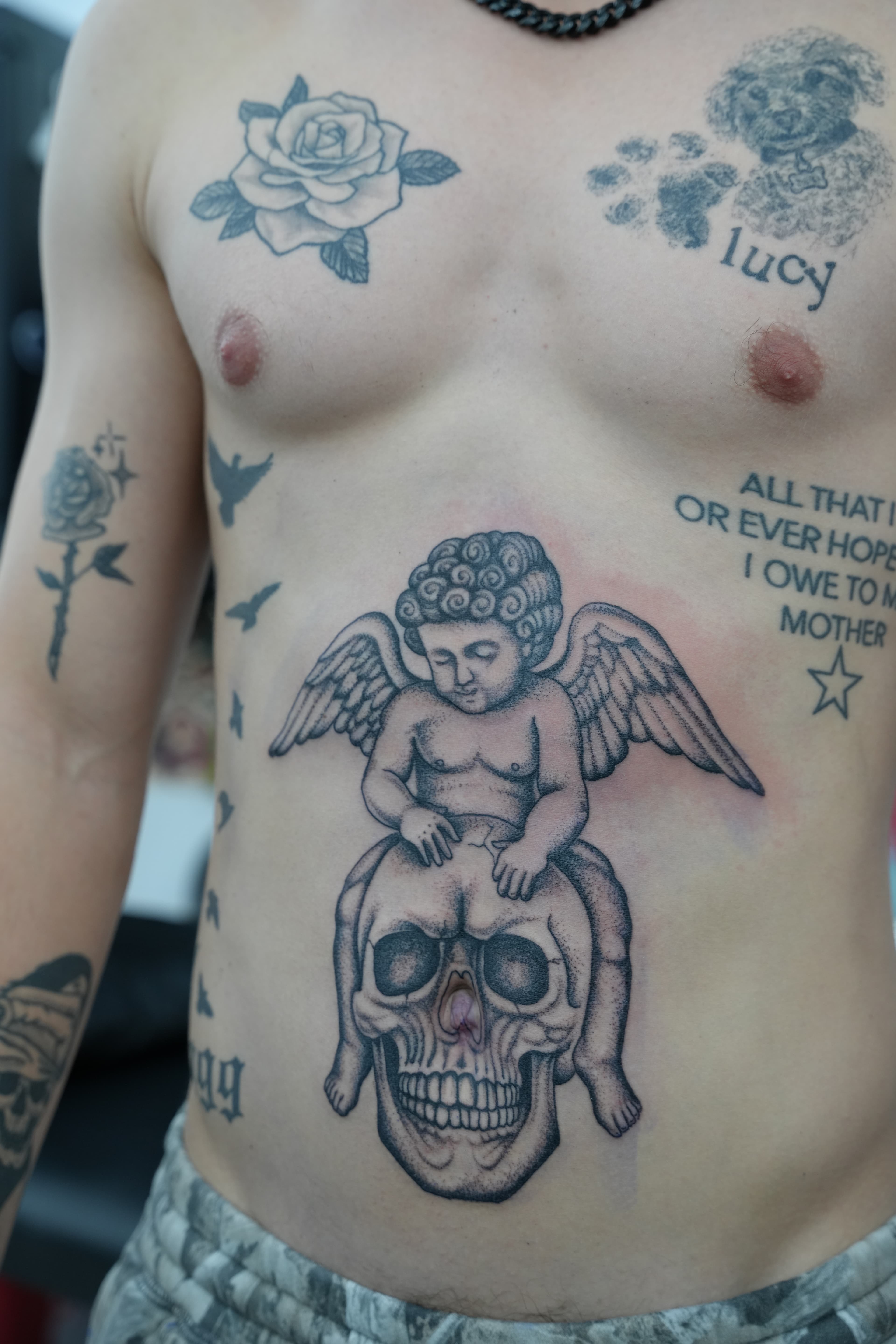 Fine line cherub and skull stomach piece tattoo by Isaac Mackenzie
