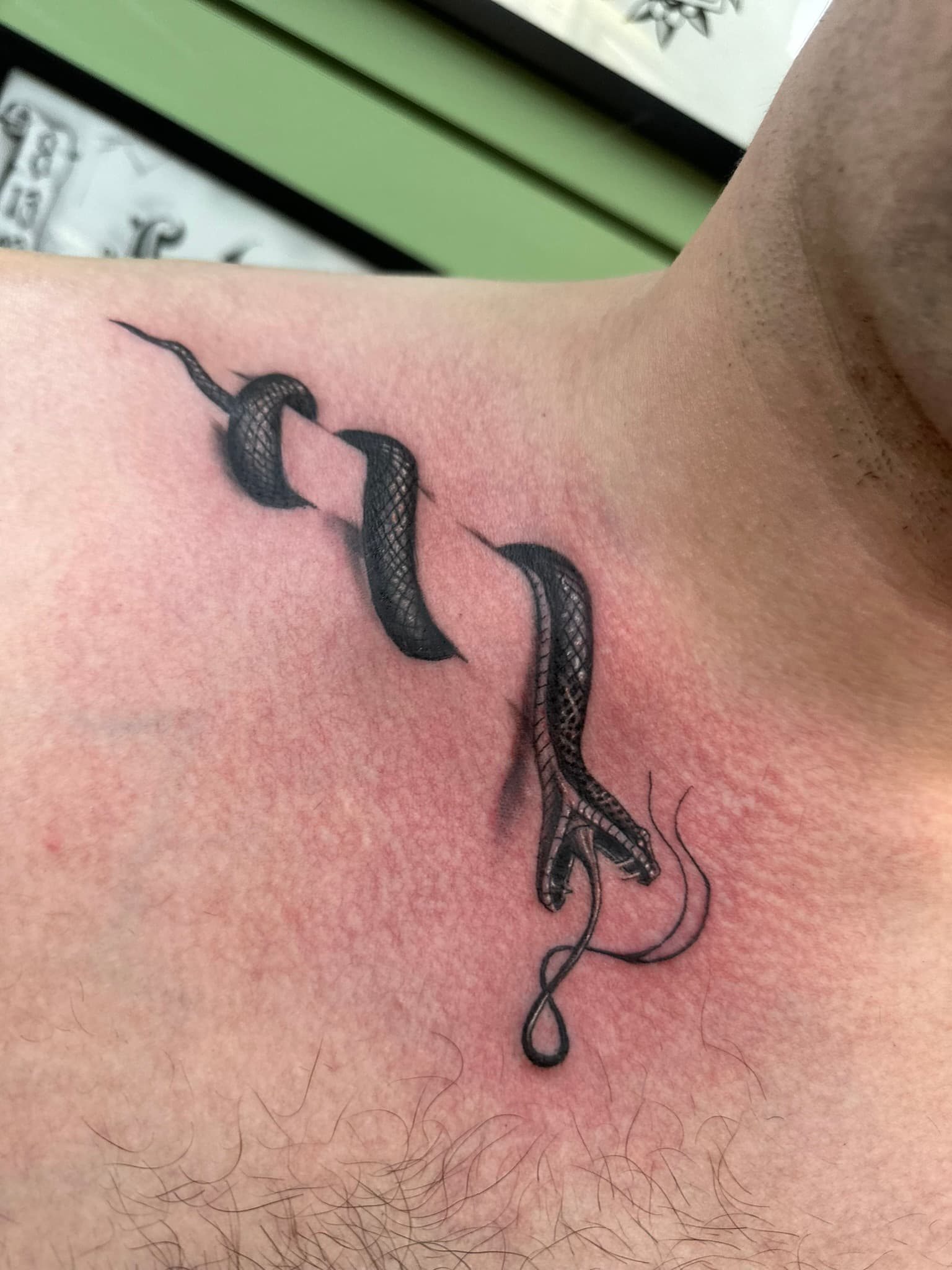 Fine line snake wrapping the collarbone tattoo by Isaac Mackenzie