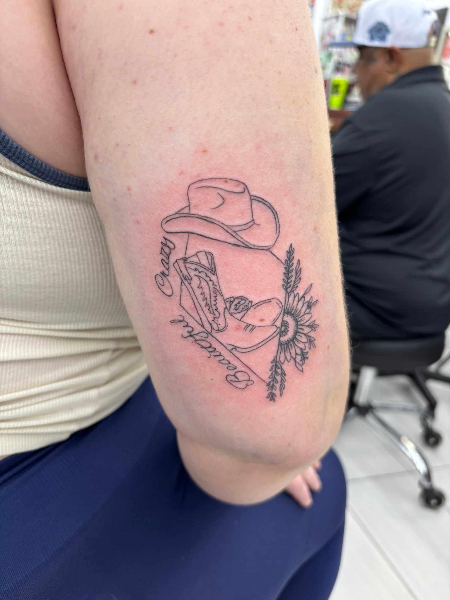Fine line cowboy boots, hat, and sunflower with script tattoo by Isaac Mackenzie