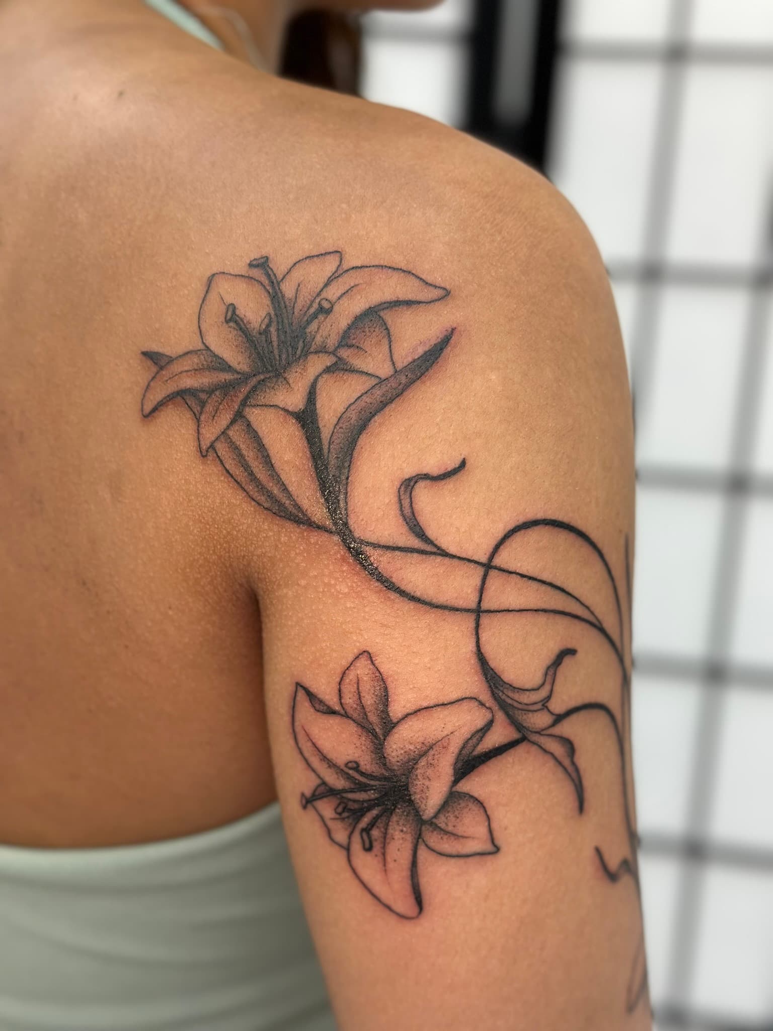 Fine line whimsical arm lilies tattoo by Isaac Mackenzie