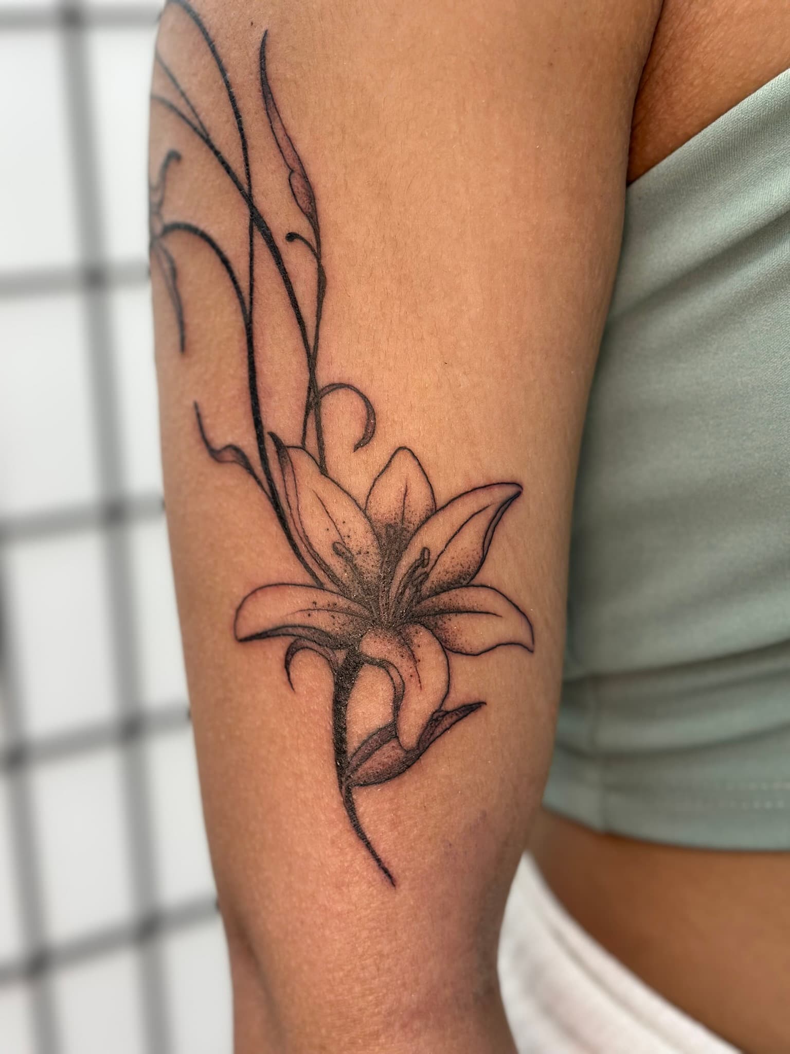 Fine line whimsical arm lilies tattoo by Isaac Mackenzie, Hawaii